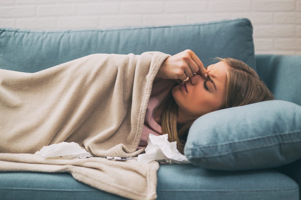 Woman with allergies lying down on couch.