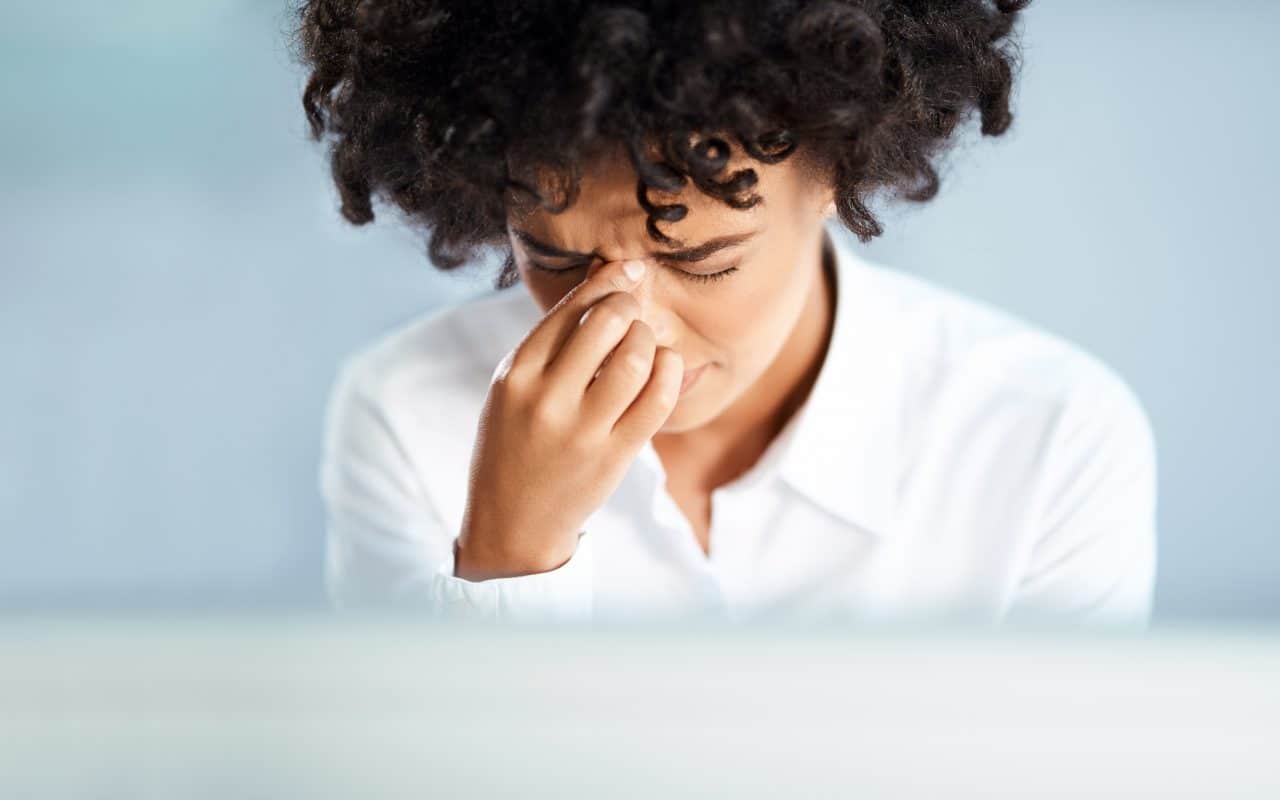 Woman experiencing sinus pressure from allergies.