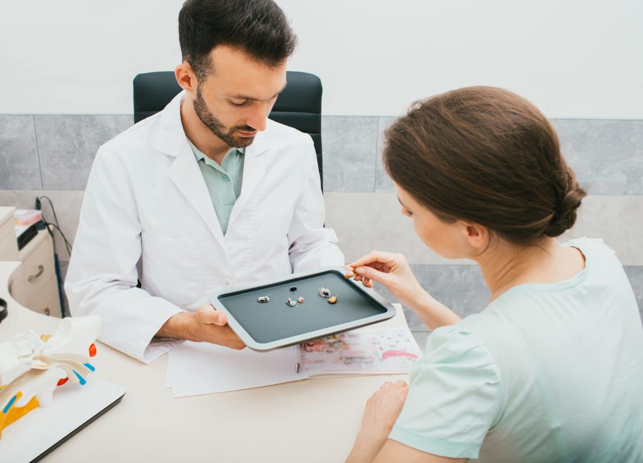 Woman picking out a new hearing aid with the help of her audiologist.