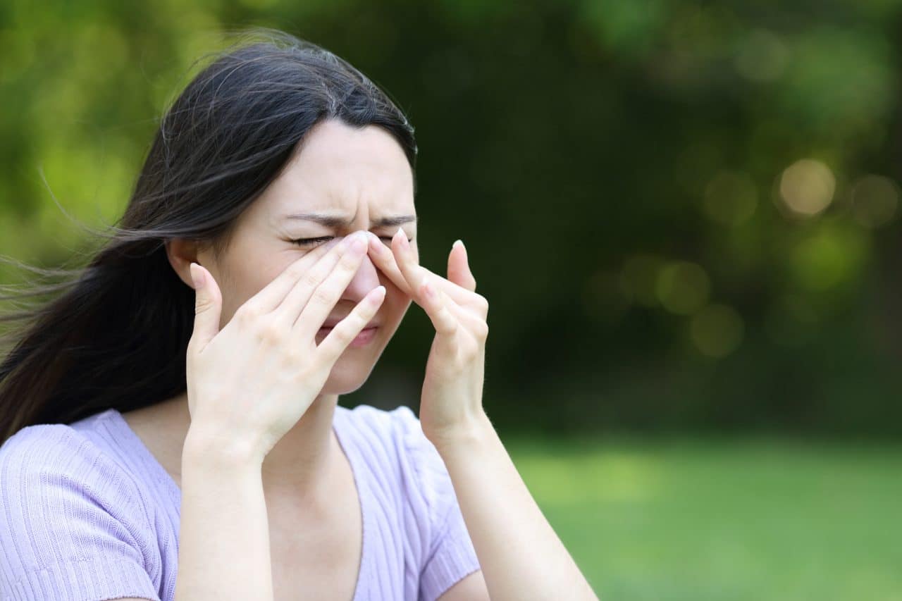 Women experiencing allergy symptoms outdoors.