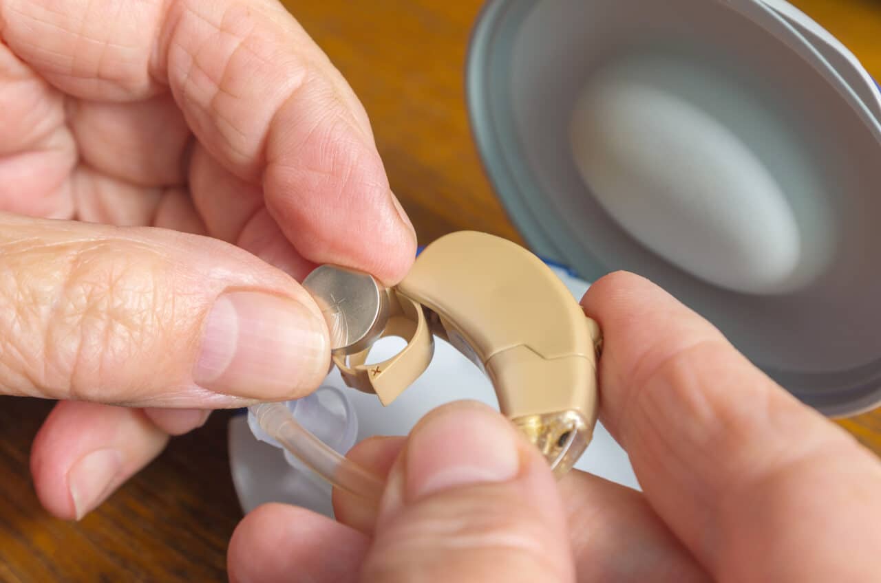 Woman changes the battery in her hearing aids.