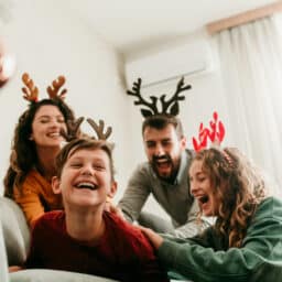 Family laughing together wearing reindeer headbands