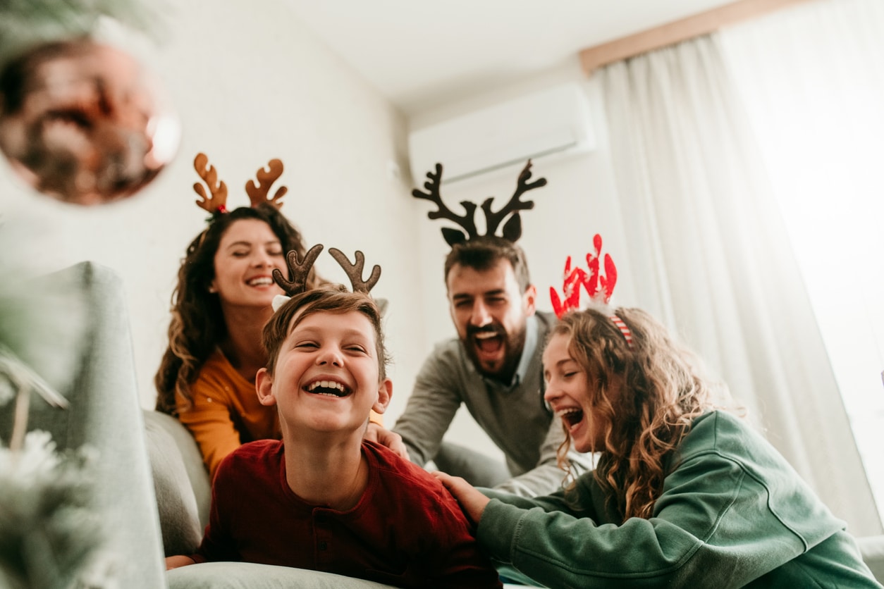 Family laughing together wearing reindeer headbands.