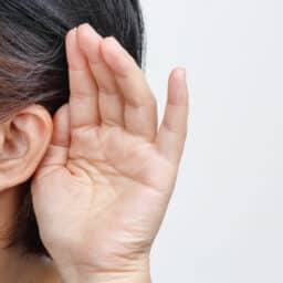Person cups hand behind ear to hear