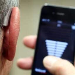Man with hearing aid uses a hearing aid app
