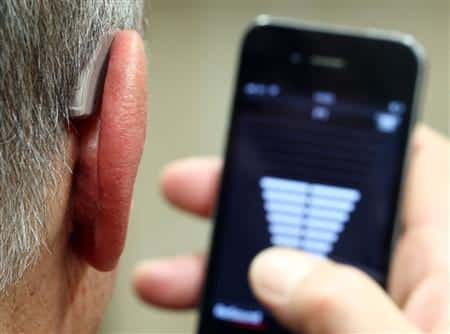 Man with hearing aid uses a hearing aid app